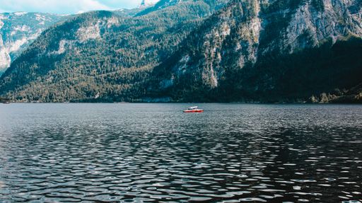 The Hallstatt lake with a small boat and a giant mountain