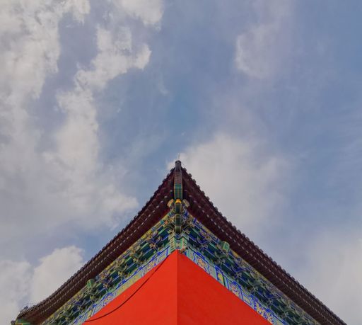 A closeup of a red roof details of an Asian style palace under a cloudy sky