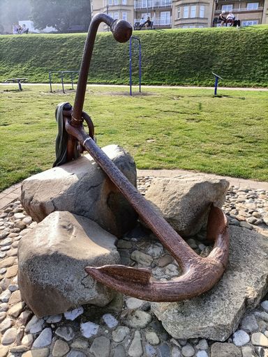 A vertical closeup shot of an anchor monument surrounded by broken stone