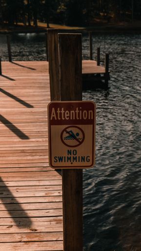 A vertical of a no swimming sign on the pier.
