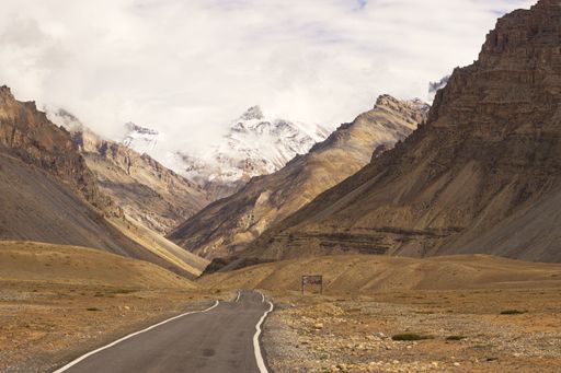 An aerial view of road surrounded by greenery fields in background of mountains