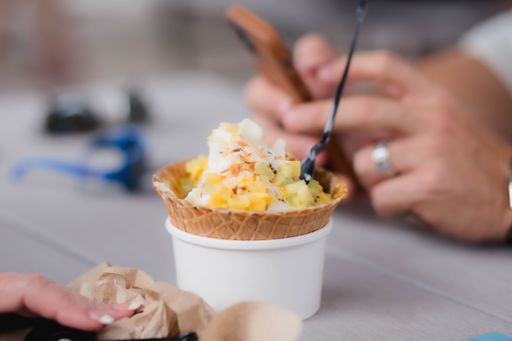 A selective focus of ice cream with sprinkles in a cone and a spoon on a table
