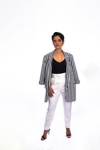 A vertical portrait of a businesswoman in a formal outfit standing in front of a white background