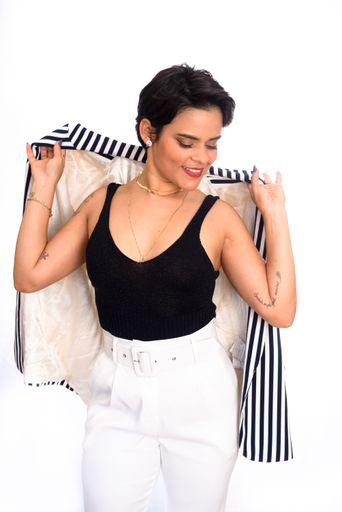 A vertical portrait of a businesswoman in a formal outfit standing in front of a white background