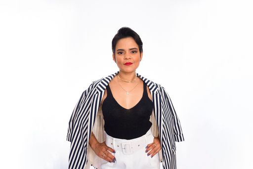 A portrait of a businesswoman in a formal outfit standing in front of a white background