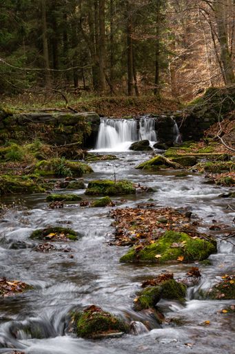A long exposure shot of the cascade waterfall surrounded by the mossy rocks in the forest