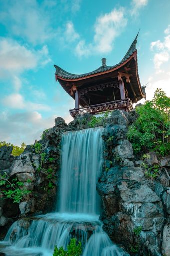A vertical shot of the pagoda and waterfall in Fukushuen Chinese Garden in Naha Okinawa, Japan
