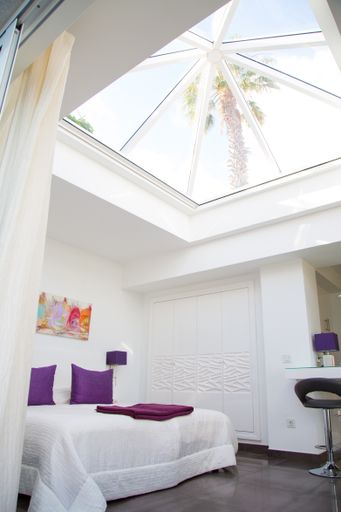 A vertical shot of a beautiful white bedroom interior design with a bed under a huge glass ceiling