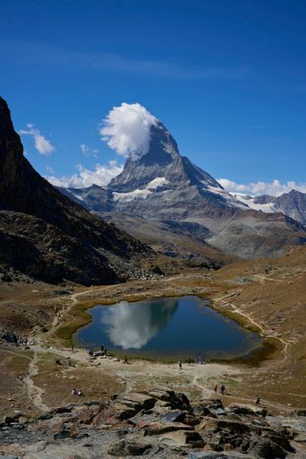 A vertical shot of a small lake with the huge Matterhorn mountain in the background