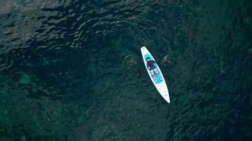 An aerial view of a person in a kayak floating on the water in Bali, Indonesia