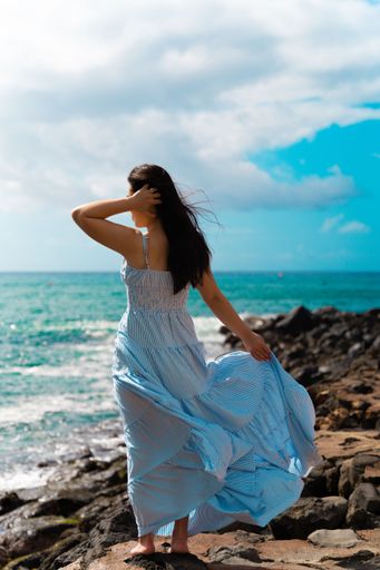 A vertical shot of a woman in a long dress posing in Honolulu, Hawaii