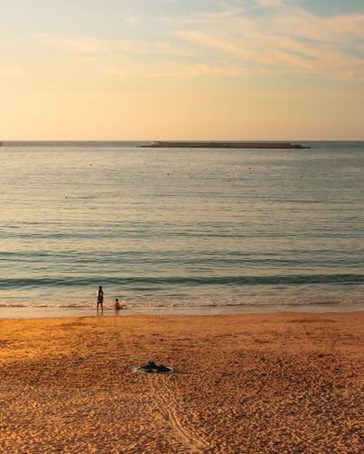 A vertical shot of two kids relaxing on the beach on a sunny day