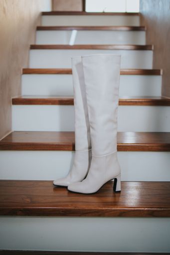 A vertical shot of white leather boots on the wooden stairs at home