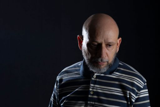 A handsome bald man with beard wearing a casual shirt over black background, Thinking worried