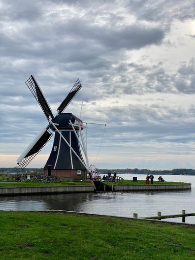 A vertical shot of a Windmill near the coast of a lake in Groningen, Netherlands