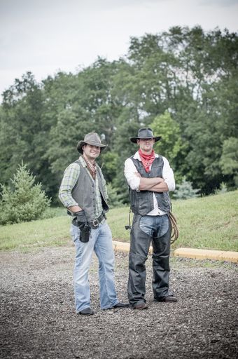 A vertical shot of two males wearing a cowboy outfit and standing near each other