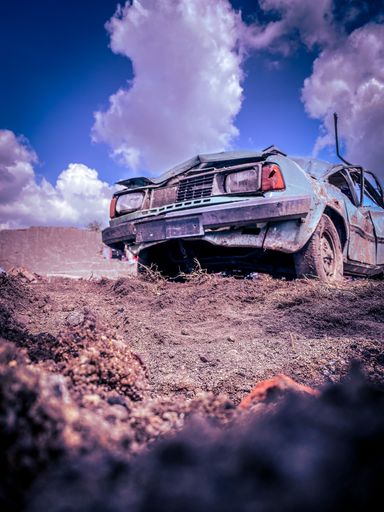 A vertical shot of a broken old vintage car abandoned in the nature