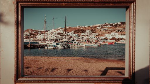 The picture of the famous island of Mykonos in a gold frame, fixed on the wall