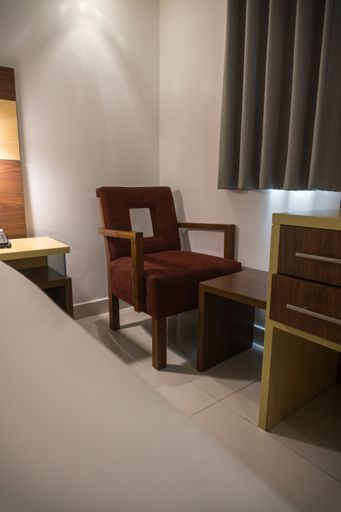 A vertical shot of a cozy bedroom with a chair and a reading table.