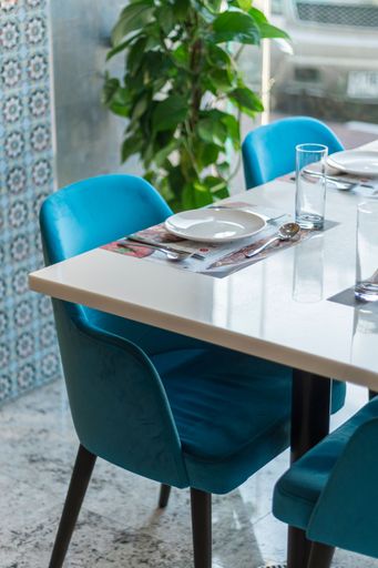 A vertical shot of blue chairs and cutlery on the table in the restaurant.