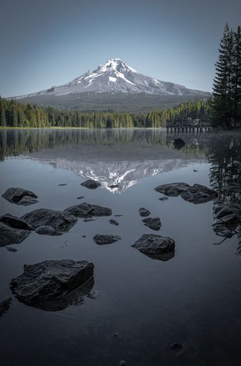 A vertical shot of the smooth lake and green woods with Mount Hood in the background. Oregon, USA.