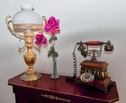 A vintage telephone on the hall table with a lamp and pink flowers