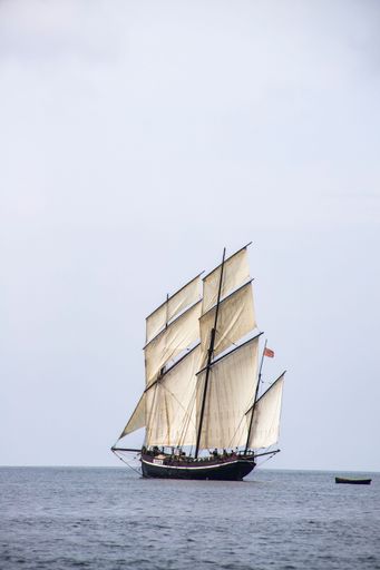 A vertical shot of a sailing ship in the middle of the sea