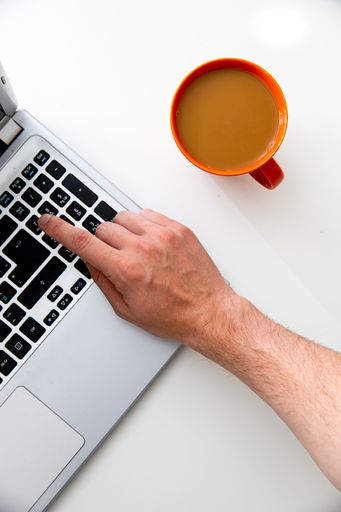 A top view of a young businessman working on a laptop with a cup of coffee on the table