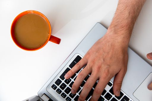 A top view of a young businessman working on a laptop with a cup of coffee on the table