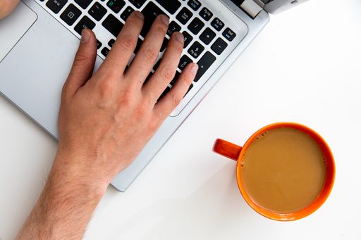 A top view of a young businessman working on a laptop with a cup of coffee on the table
