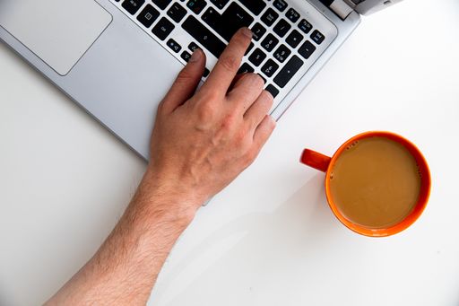 A top view of a young businessman working on a laptop with a cup of coffee on the table