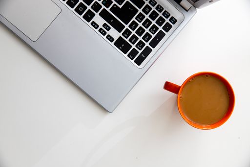 A top view of a modern gray laptop and a cup of coffee on the table