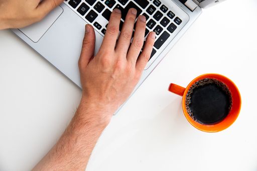 A top view of a young businessman working on a laptop with a cup of coffee on the table