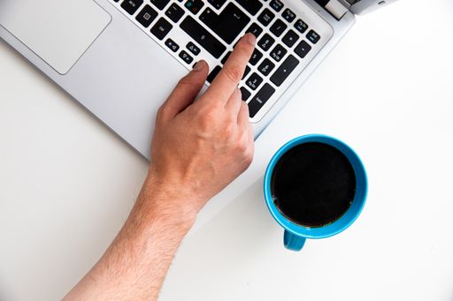 A top view of a young businessman working on a laptop with a cup of coffee on the table
