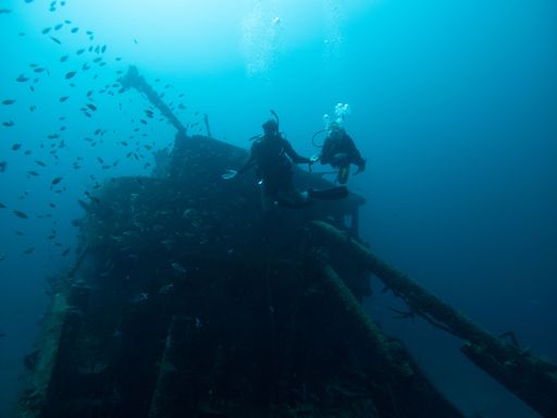 A scuba diver near a wrecked old ship underwater