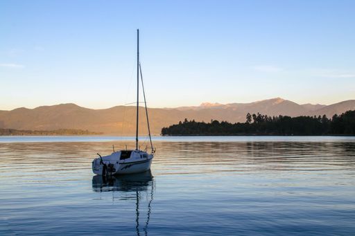 A sailboat sailing across a body of water with a mountain view in the background, Chile