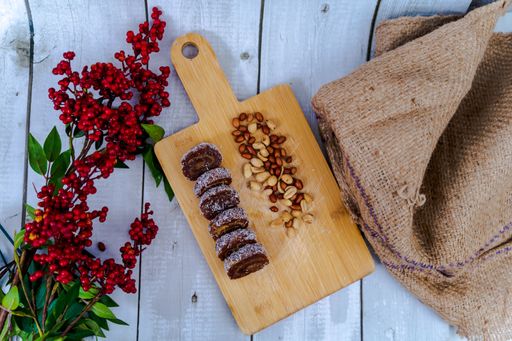 A top view of chocolate rolls covered in sesame seeds on a wooden board on a white background