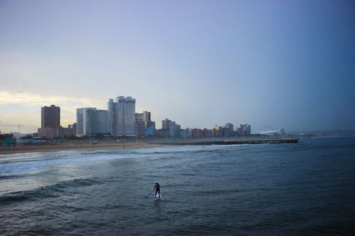 A beautiful view of a surfer in the sea with the Durban skyline in the background, South Africa
