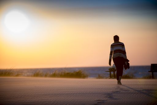 A beautiful shot of a female walking on a sandy shore leaving footprints behind