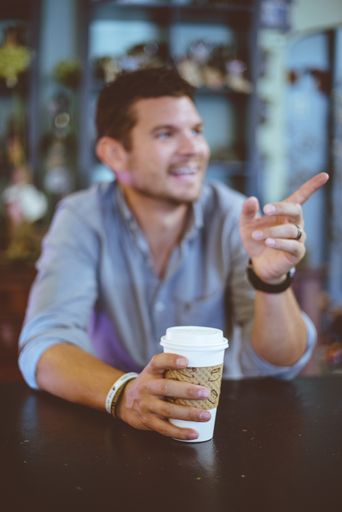 A vertical shot of a male sitting in the cafe and pointing outside