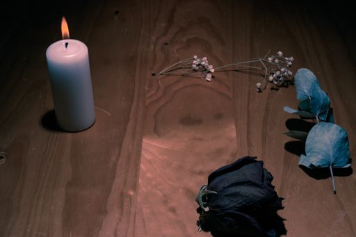 A closeup of a candle on the floor with dried flowers on it
