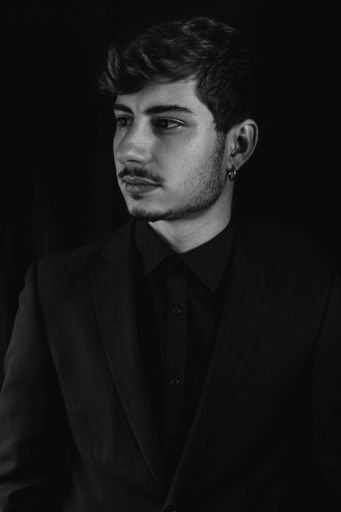 A vertical closeup shot of a handsome guy on a coat and tie isolated on a dark background