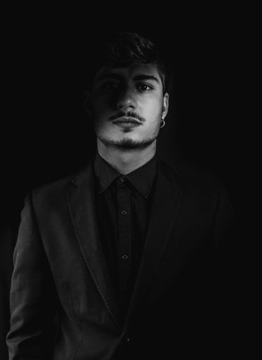 A grayscale shot of a cool and handsome guy wearing a dark coat