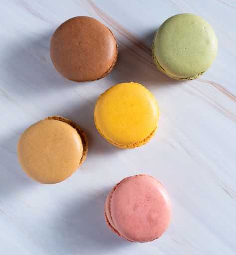 A vertical top view of colorful macarons on a table