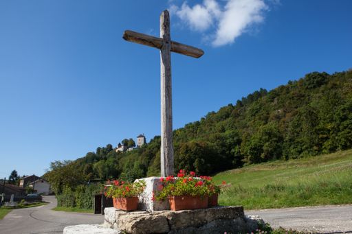 A low angle shot of a wooden cross on a clear sky and a mountain background