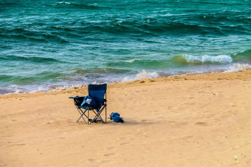 A folding chair at the beach surrounded by the sea under the sunlight