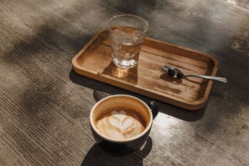 A top view of a cup of  cappuccino with a cup of water on a table