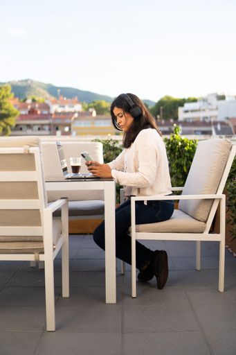 A vertical shot of a Caucasian woman working with a laptop in the cafe