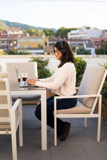 A vertical shot of a Caucasian woman working with a laptop in the cafe