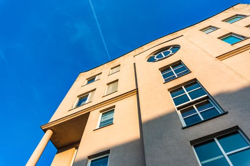 A low angle shot of a modern residential building with blue windows under the sunlight